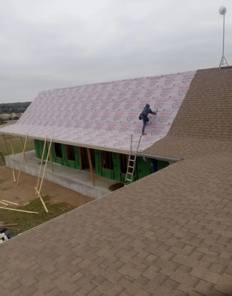 Worker preparing underlayment for a metal roof installation in Meridian